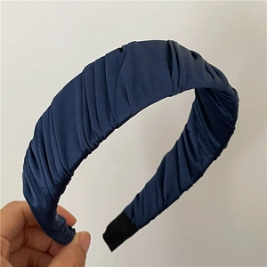 Détail de la texture satinée plissée bleu marine et des embouts de confort du serre-tête élégant