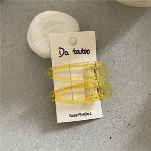 Detailed macro view of two translucent yellow waterdrop hair clips on a beige card display