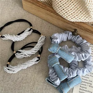 Blue denim bow scrunchies and white faux pearl elastic hair bands on a rustic linen background