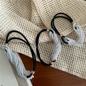 Close-up of three black elastic hair ties featuring white faux pearl beaded clusters