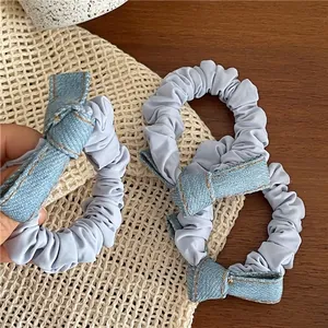 Three-piece set of light blue denim bow scrunchies with elegant orange stitching details