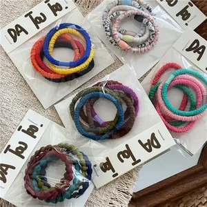 Close-up of colorful ruffled elastic hair ties set on a minimalist cream background texture