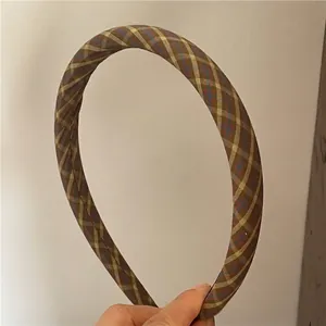 Detail showing the brown and khaki argyle plaid fabric texture on a padded headband