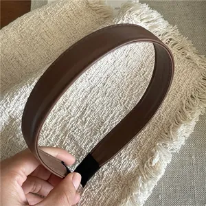 Detail of a dark brown faux leather headband with fine stitching and elastic band