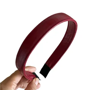 Burgundy faux leather headband with stitching detail held against white background
