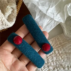 Detailansicht der dunkelgrünen gestrickten Haarspange mit roten Perlenverzierungen