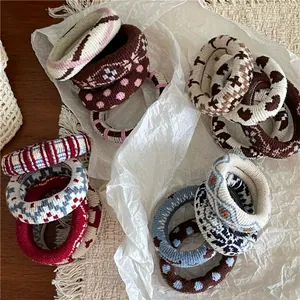 Détail de chouchous en tricot avec motifs de cœurs et carreaux aux tons terreux