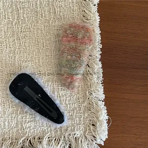 Detail of colorful knitted plush hair clip and back view of black metal snap base