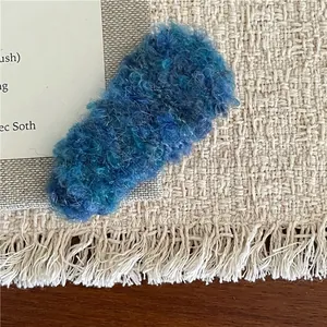 Detailed macro view of the fuzzy blue-green plush texture on a rectangular BB hair clip