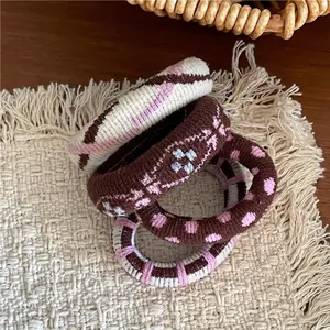 Détail de quatre chouchous en tricot à carreaux et pois sur un tapis beige tressé