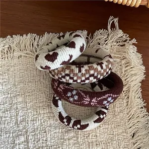 Vue détaillée de quatre chouchous tricotés avec motifs cœurs et damiers sur un tapis tissé