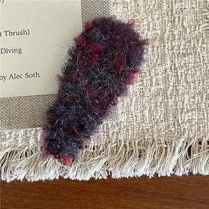 Close-up of mixed color plush snap hair clip on a textured beige woven fabric background