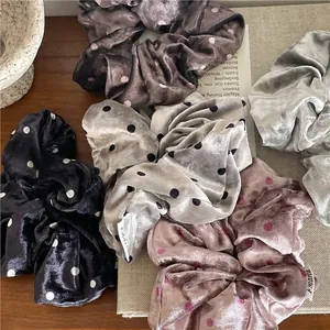 Velvet polka dot scrunchie set in assorted colors on a rustic wooden tabletop