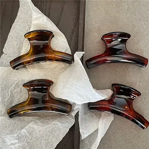 Detail view of four tortoiseshell hair claws with amber resin texture on a wooden tray