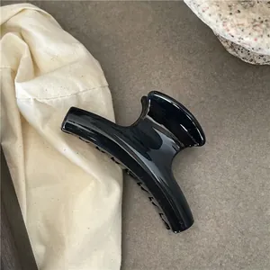 Close-up of a glossy black resin hair claw clip with a crescent-shaped design