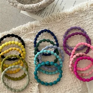 Macro detail of elastic wavy hair ties in Morandi colors on white woven fabric