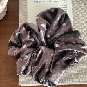 Detailed view of velvet polka dot scrunchie placed on vintage book with soft lighting