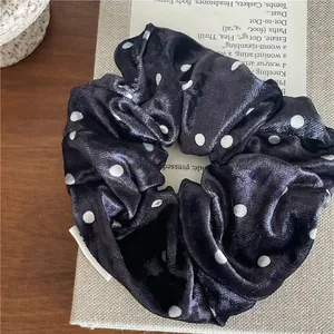 Detail of black velvet scrunchie with white polka dots on vintage book background