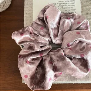 Detail of soft velvet scrunchie with polka dot pattern on a wooden surface