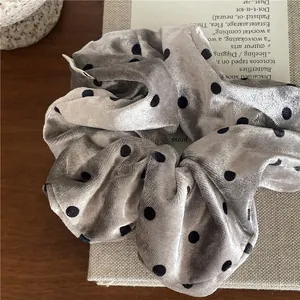 Detailed view of grey velvet scrunchie with black polka dots on vintage background