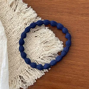 Detailed shot of a navy blue elastic hair tie with wavy texture on a woven coaster