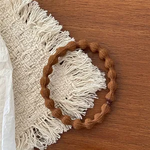 Close-up of brown bubble textured fabric hair tie on a warm minimalist desktop background