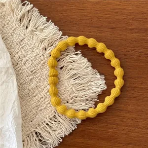 Detailed shot of yellow elastic hair band with beaded texture on woven mat