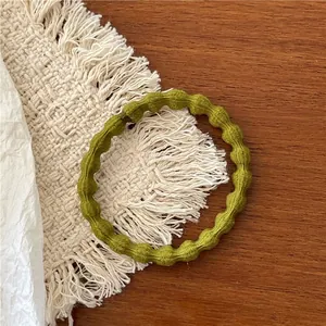 Detail of olive green knitted hair scrunchie with unique wavy texture on wooden surface