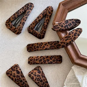 Various leopard print plush hair clips in geometric shapes on a warm aesthetic background