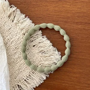 Detail of sage green ribbed elastic hair tie on a rustic wooden tabletop