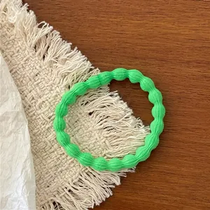 Detail of a grass green ribbed elastic hair scrunchie on a woven mat and wood surface
