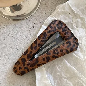 Detailed view of a leopard print BB hair clip with soft faux fur on a textured stone base