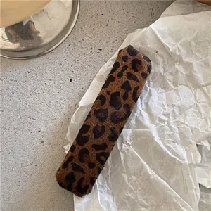 Detail of a rectangular leopard print plush hair clip on a white textured background