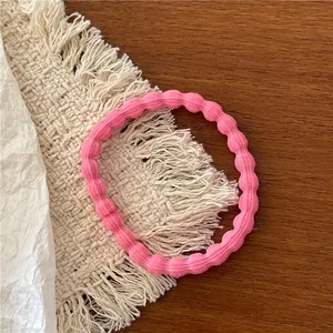 Close-up of pink elastic hair tie with wavy texture on a rustic wooden surface