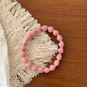 Close-up of a pink elastic hair tie with wave texture on a minimalist wooden background