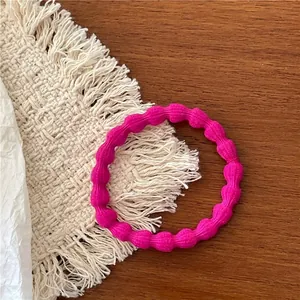 Close-up of rose red textured elastic hair tie on a beige woven mat background