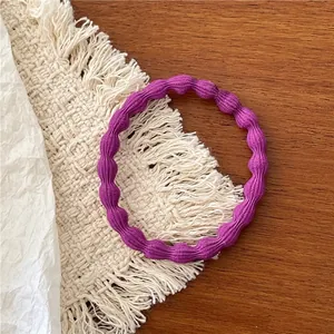 Detailed macro view of a purple wavy elastic hair tie on a decorative woven mat