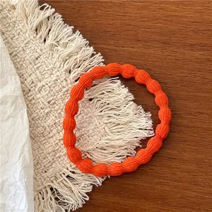 Detail of bright orange wave-patterned hair tie on a rustic wooden table setting