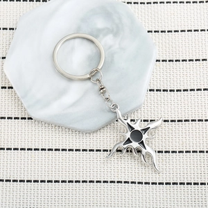 Detail view of silver gothic cross keychain with black enamel on marble display stand