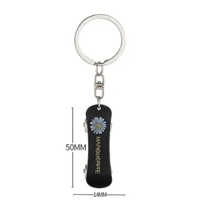 Skateboard daisy keychain in black with Marguerite text and dimensions 50mm by 14mm