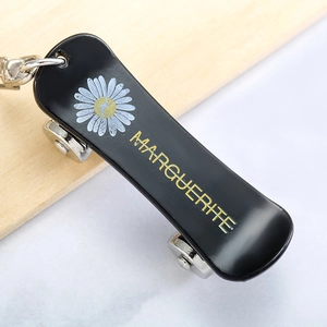 Creative daisy skateboard keychain with black finish and silver wheels on a marble surface