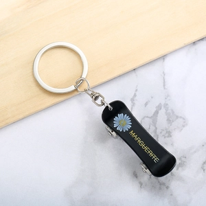 Creative skateboard keychain with blue daisy motif and silver ring on a marble surface
