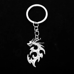Tribal style silver metal dragon keychain with lobster clasp on black background