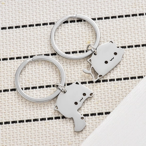 Close-up of cute stainless steel cat keychains on a textured woven mat background
