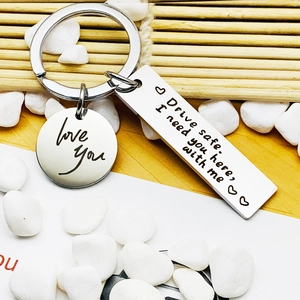 Macro shot of silver stainless steel Drive Safe keychain charms on bamboo background