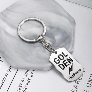 Polished silver metal dog tag keychain with Golden Hardware engraving on marble base