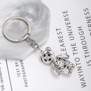 Silver hollow out metal bear keychain with heart pattern on marble and printed book page