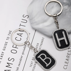 Detail of hip hop rhinestone square pendants with letters B and H on marble background