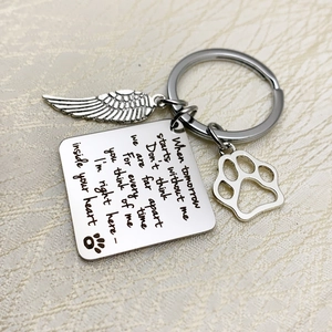 Macro detail of memorial keychain with engraved poem wing charm and pet paw pendant