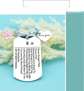 Detail of engraved steel keychain with pink flower charm and heart pendant for lover
